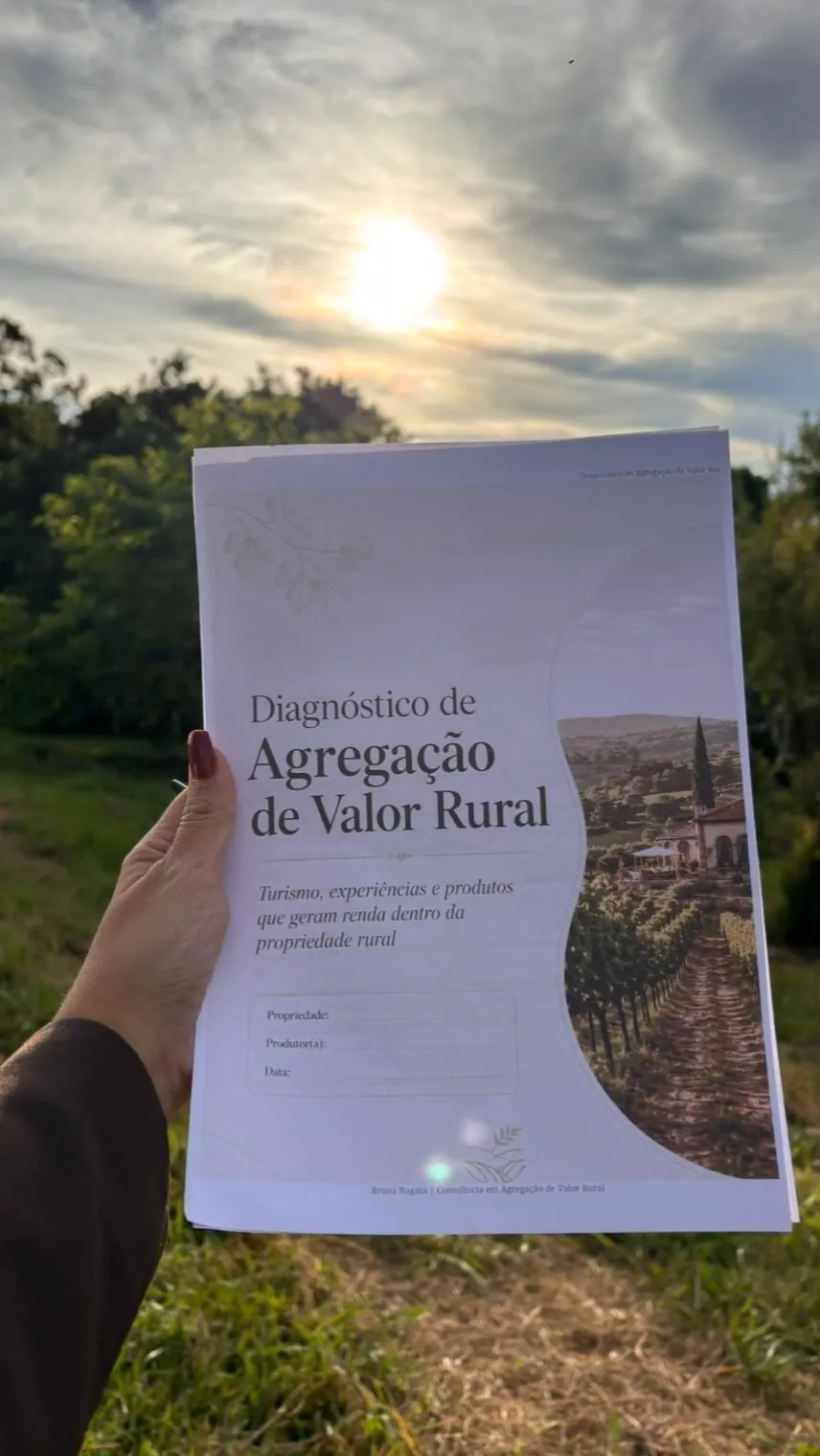Mão segurando o documento Diagnóstico de Agregação de Valor Rural contra o céu, com árvores ao fundo